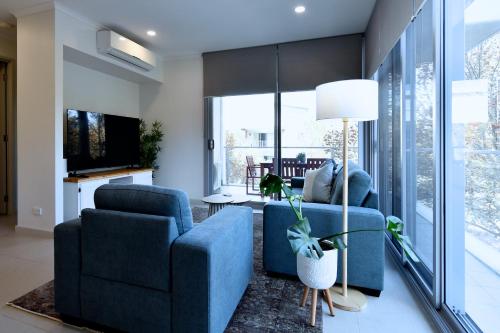a living room with two blue chairs and a television at Capri on Flinders in Rockingham