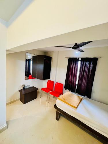 a bedroom with a bed and two red chairs at COSMO LODGE in Mangalore