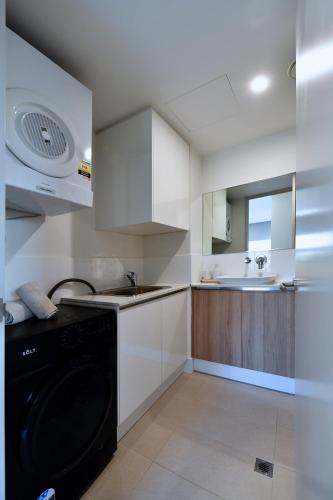 a white kitchen with a sink and a dishwasher at Capri on Flinders in Rockingham
