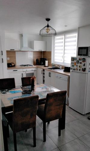 une cuisine avec une table, des chaises et un réfrigérateur dans l'établissement La petite ruette, à Le Molay-Littry