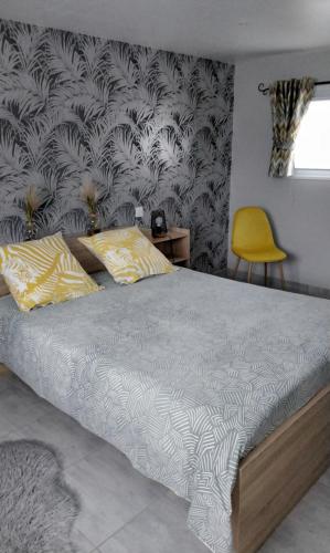 a bedroom with a bed and a yellow chair at La petite ruette in Le Molay-Littry