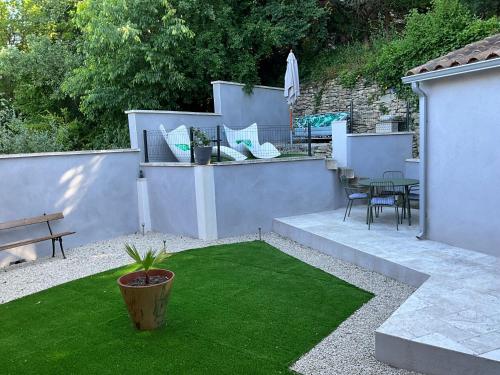 a small yard with a patio with green grass at Le petit bastidon gîte à Oppède avec piscine in Oppède
