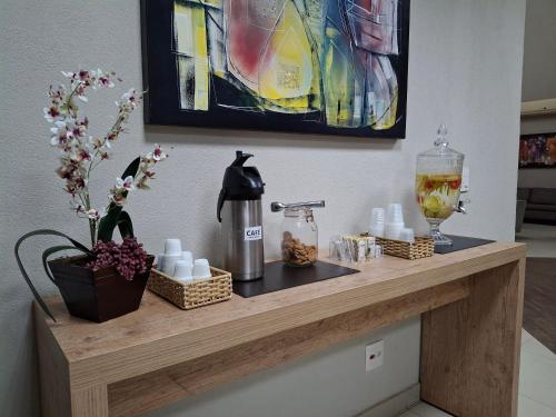 a counter with a coffee maker and flowers on it at Ônix Inn Hotel Cravinhos in Cravinhos