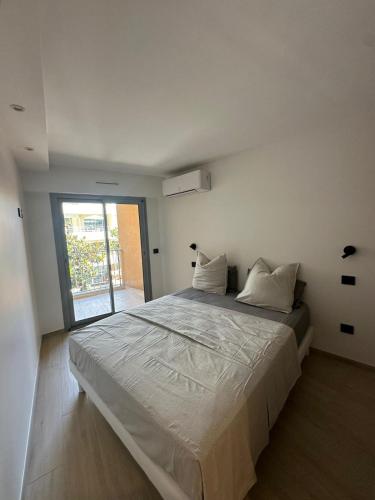 une chambre blanche avec un grand lit et une fenêtre dans l'établissement LES ALLIES - T2 Cavalaire sur Mer, à Cavalaire-sur-Mer