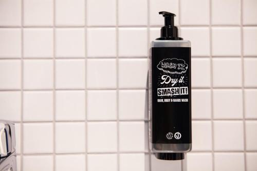 a black bottle of mouthwash on a white tiled wall at ibis budget Hotel Berlin Airport in Berlin