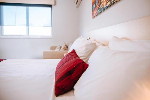 a red pillow sitting on top of a white bed at Comfort Inn Moree in Moree