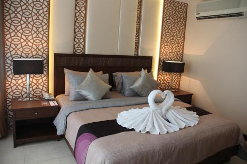 two white swans on a bed in a hotel room at De Arni Bangkok - SHA Extra Plus in Bangkok