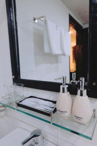 a bathroom sink with a mirror and two soap dispensers at Canary Boutique Hotel in Hue