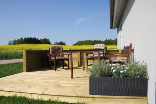 a patio with three chairs and a table with a field in the background at Hellerup Bed & Breakfast in Løgstrup
