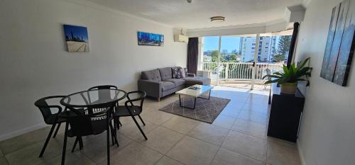 a living room with a glass table and a couch at Broadbeach Holiday Apartments in Gold Coast