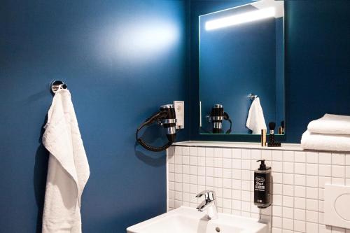 a blue bathroom with a sink and a mirror at ibis budget Hotel Berlin Airport in Berlin