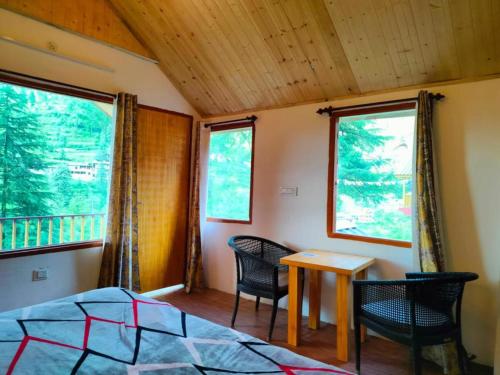 ein Schlafzimmer mit einem Bett und einem Tisch und zwei Stühlen in der Unterkunft Majestic View Cottages in Jibhi