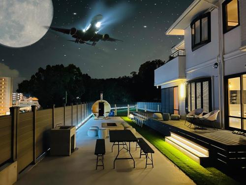 an airplane is flying over a house at night at New AirportHills 1400ｍ2 絶景露天風呂1棟2階貸切 駐車場4台 サウナ BBQ施設 ペット in Hakata