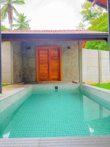 a house with a swimming pool with a door in it at Villa Lee in Ragama
