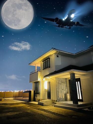 a plane is flying over a house with a moon at New AirportHills 1400ｍ2 絶景露天風呂1棟2階貸切 駐車場4台 サウナ BBQ施設 ペット in Hakata