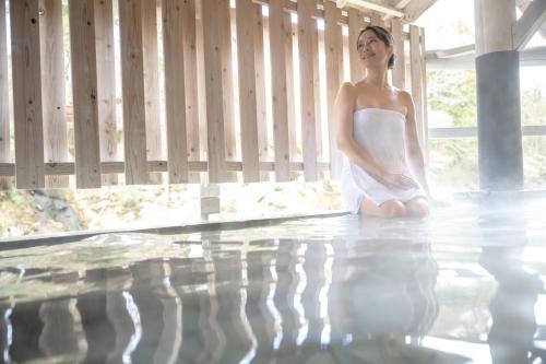 a woman in a white dress sitting next to a swimming pool at Sakan in Sendai