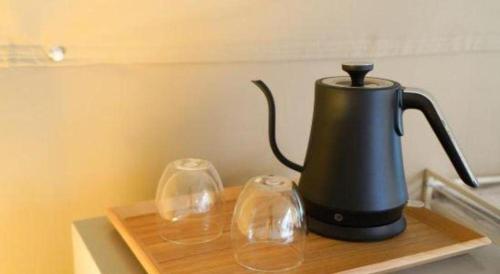 a black tea kettle and two glasses on a cutting board at Kyoto Keburikawa Hotel in Kameoka