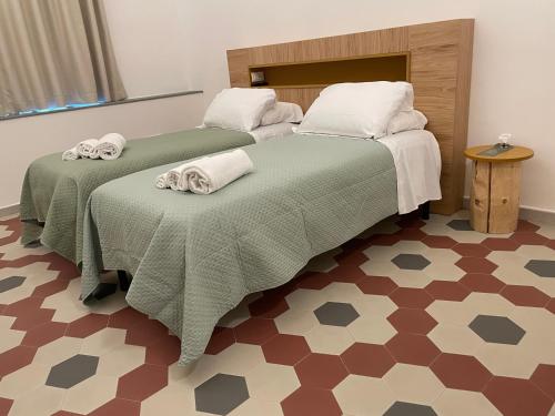 two beds in a room with green blankets and towels at Il Genio - Residenza D'Epoca in Pisa