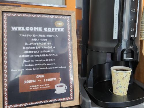 a sign next to a coffee machine with a cup at APA Hotel Karuizawa Ekimae Karuizawaso in Karuizawa