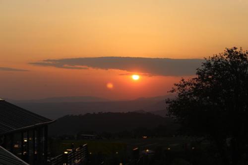 a sunset in the mountains with the sun hiding behind a cloud at Billing View Camp and Mud Houses,Bir in Aiju