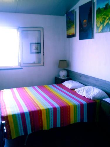 a bed with a colorful blanket on it in a bedroom at Casa paradisoTaorminaEtna in Piedimonte Etneo