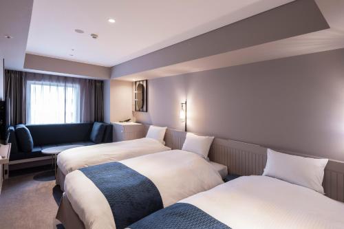 a hotel room with two beds and a couch at HOTEL TORIFITO KANAZAWA in Kanazawa