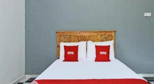 a bedroom with a bed with two red pillows at OYO 90507 Chalet Sumayyah in Melaka
