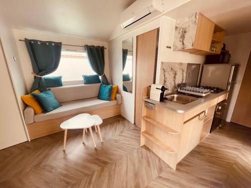 Cette petite chambre comprend une petite cuisine avec un canapé. dans l'établissement Mobil Home Jasmins 3, à Valras-Plage
