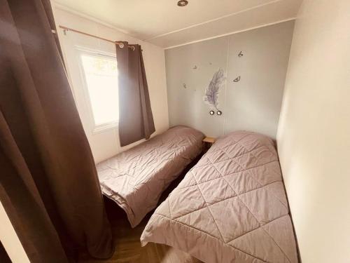 une petite chambre avec deux lits et une fenêtre dans l'établissement Mobil Home Jasmins 3, à Valras-Plage
