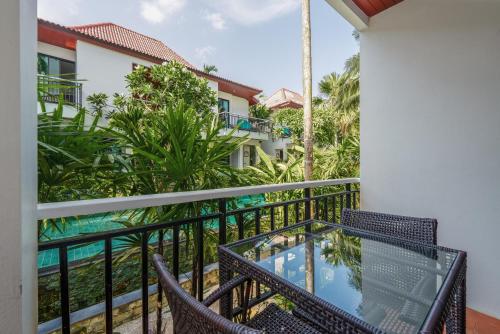 a balcony with chairs and a view of a house at Coco Retreat Phuket Resort and Spa - SHA Plus in Chalong