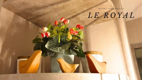 a vase with flowers sitting on a table with chairs at Le Royal Benson Apartment at Supermal Pakuwon in Surabaya