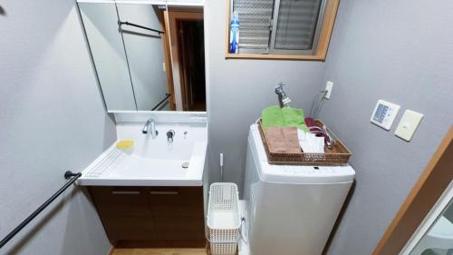 a bathroom with a sink and a toilet and a mirror at 駅徒歩1分 観光拠点に最適なゆったり快適一軒家 in Osaka
