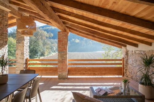 a patio with a table and chairs and a wooden ceiling at L'Eixida in Sant Jaume de Llierca