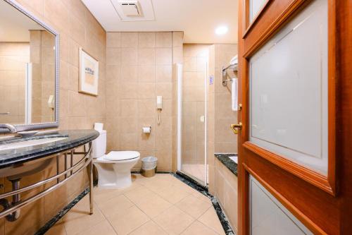a bathroom with a toilet and a sink and a shower at Wei-Yat Grand Hotel in Tainan