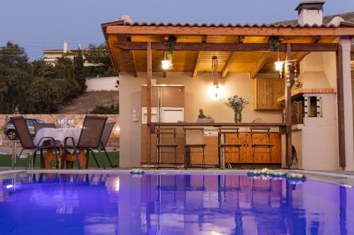 a patio with a table and a kitchen and a swimming pool at RELAXING POOL HOUSE IN LAGONISI 1 in Kalívia Thorikoú