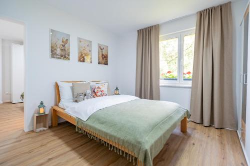 a white bedroom with a bed and a window at Apartment under the Larch in Jesenice