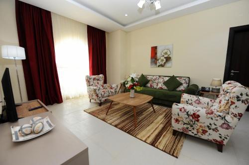 a living room with a green couch and chairs at Al Mansour Park Inn Hotel&Apartment in Doha