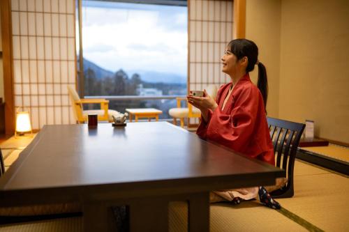 a woman sitting at a table looking at her cell phone at Sakan in Sendai