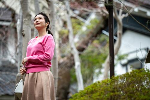 a woman wearing a pink sweater and a skirt at Sakan in Sendai