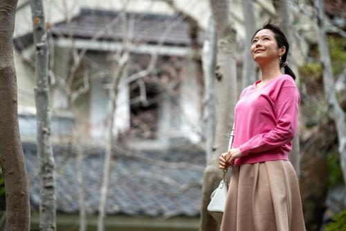 a woman is standing in front of a house at Sakan in Sendai