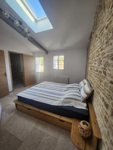 un grand lit dans une pièce avec un mur de briques dans l'établissement La Petite Maison d Exireuil, à La Celle-sous-Gouzon
