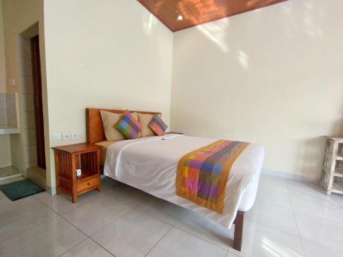 biała sypialnia z łóżkiem i stolikiem nocnym w obiekcie Meme Lan Bape Guest House w mieście Ubud