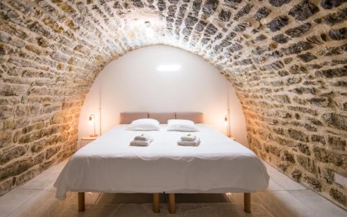 une chambre avec un lit dans un mur de briques dans l'établissement Le boum coeur douillet troglodyte jardin wifi pk, à Millau