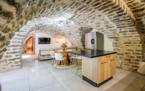 une cuisine et une salle à manger avec un mur en briques dans l'établissement Le boum coeur douillet troglodyte jardin wifi pk, à Millau