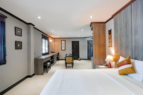 a bedroom with a large bed and a desk at Naiya Buree Boutique Resort Nai Harn Beach in Rawai Beach
