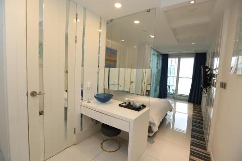 a bathroom with a sink and a bed and a mirror at Hamdeok Beach Stay Jeju in Jeju