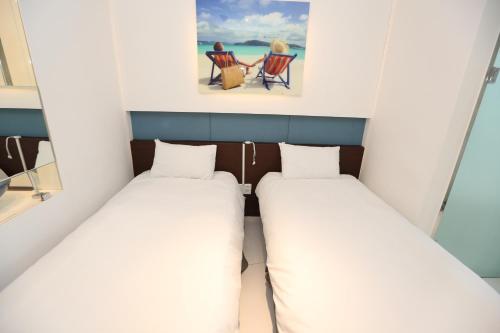 a small room with two beds and a chair at Hamdeok Beach Stay Jeju in Jeju