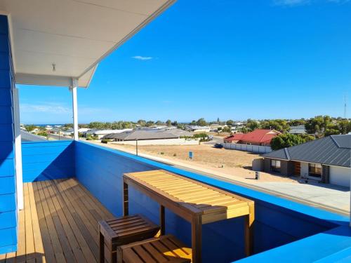 a balcony with a wooden bench and a view of a building at Azure Haven Holiday Home in Port Hughes