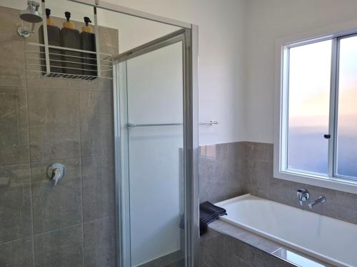 a bathroom with a shower and a tub and a window at Azure Haven Holiday Home in Port Hughes