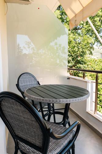 a table and chairs on a balcony with a window at Kristianna Apartments in Dhërmi